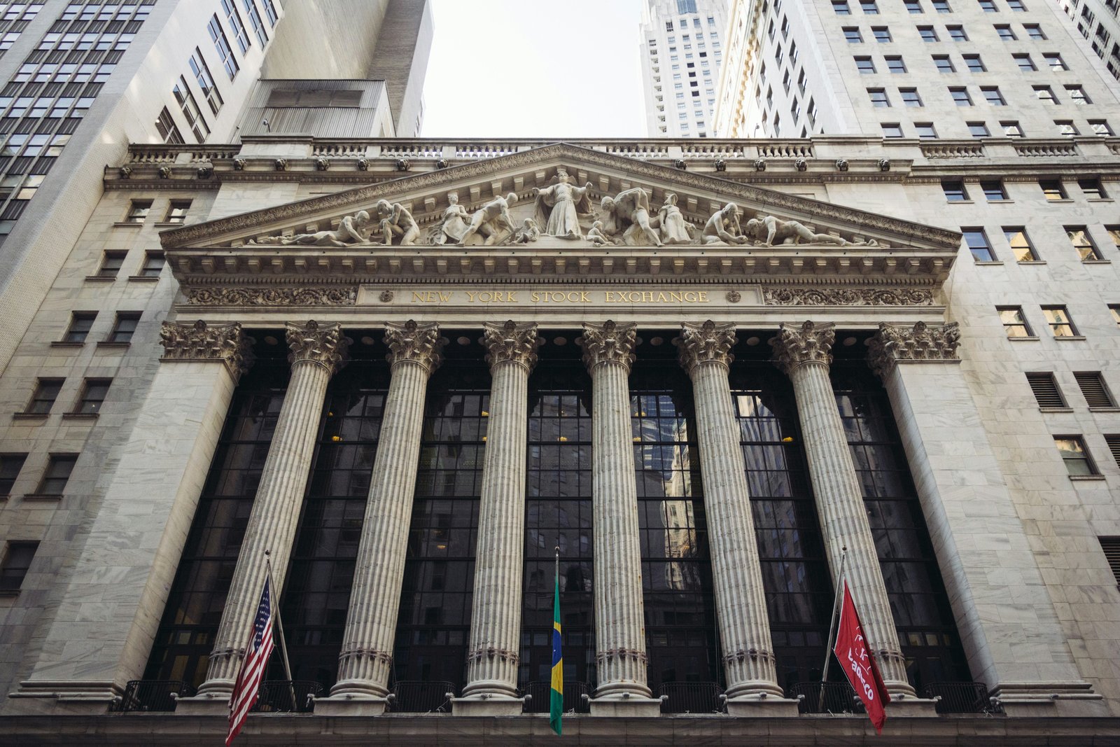 A low-angle view of the New York Stock Exchange building facade with its columns and American flag