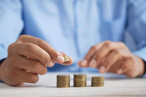 A hand stacking coins into small piles