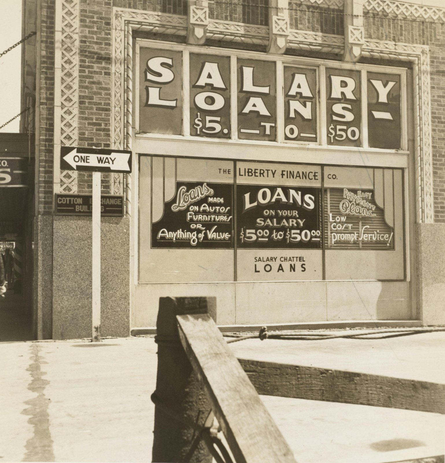A vintage black-and-white photo of a storefront reading 'Salary Loans $5 to $50,' The Liberty Finance Co., with a One Way street sign in front